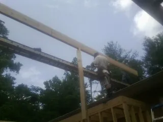 Carpenter setting a ridge beam over a new addition frame — Ice Dam Removal by Roofing Brothers in Cunningham