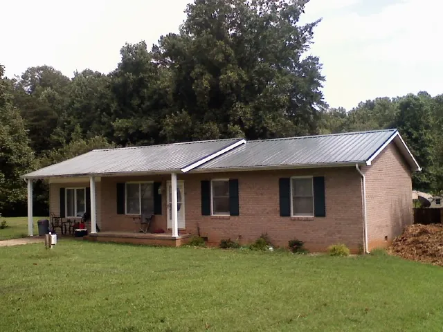 Gray metal roof on a brick ranch house with a side carport in Cunningham