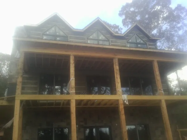 Dormers and porch framing on a large log home under construction — Roof Coating work by our crew in Cunningham