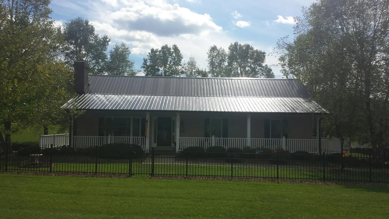 Gray metal roof on a brick ranch with a full width front porch — Gutter Guard Installation work by our crew in Cunningham